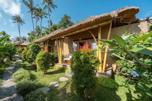 a house with a thatched roof and some plants at Rumah Kita Ecolodge in Ubud