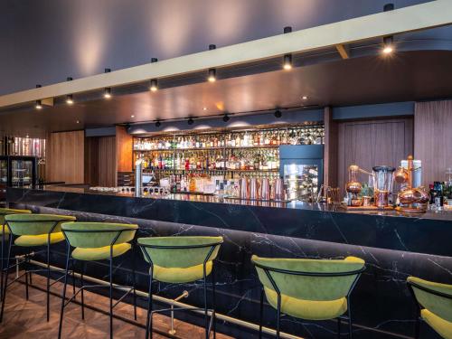 a bar with green bar stools in a room at Pullman Stuttgart Fontana in Stuttgart