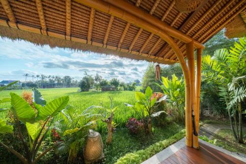 a view of a field from the porch of a house at Rumah Kita Ecolodge in Ubud