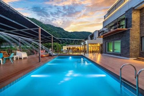 a large blue swimming pool next to a building at Gapyeong Lavita Kids Pool Villa in Yongmunch'ŏn