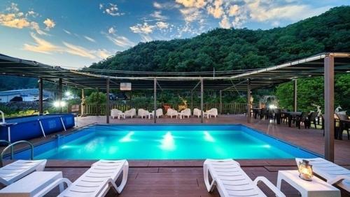 a pool with chairs and a table and a mountain at Gapyeong Lavita Kids Pool Villa in Yongmunch'ŏn