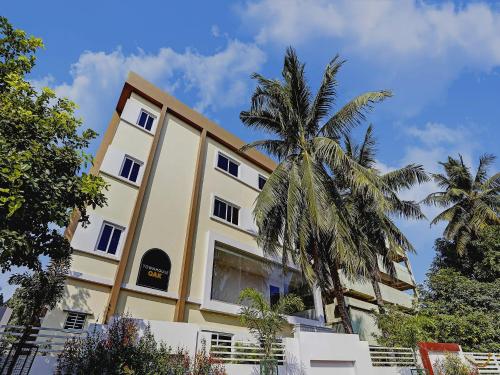 a yellow building with palm trees in front of it at Capital O De Alphabet Kakinada in Kākināda