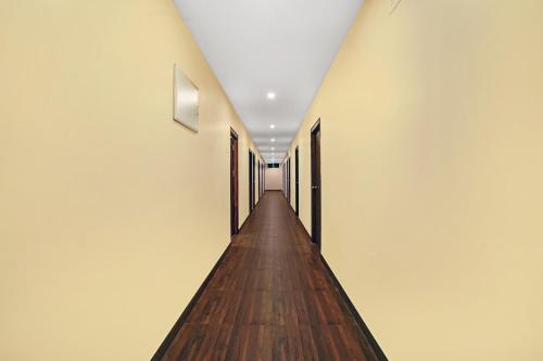 a long hallway with wooden floors and white walls at Capital O De Alphabet Kakinada in Kākināda