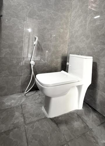 a white toilet in a bathroom with a hose at NAKSHATHRA Guest House 2BHK in Tiruvannāmalai