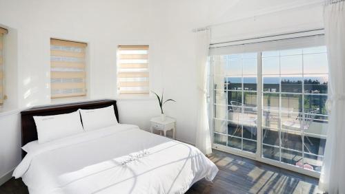 a white bedroom with a bed and a large window at Taean Janggong Pension in Yangjimal