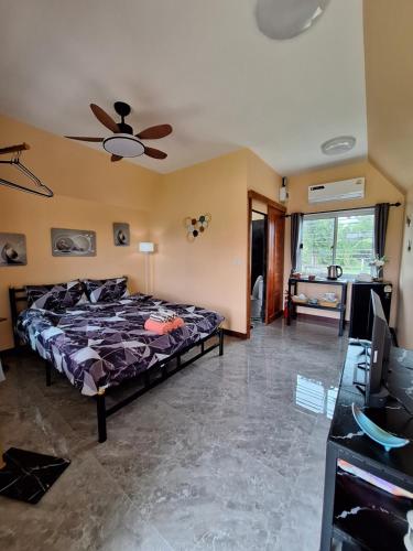 a bedroom with a bed and a ceiling fan at บ้านน้ำผึ้งโฮมสเตย์ in Suan Phung
