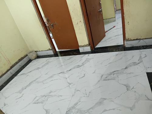 a white marble floor in a room with a door at Keshari House in Gaya