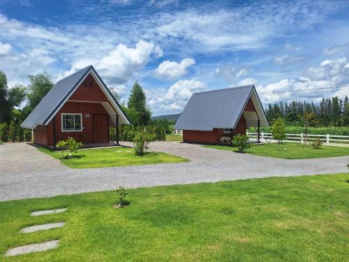 a barn and a house with a grass yard at บ้านน้ำผึ้งโฮมสเตย์ in Suan Phung
