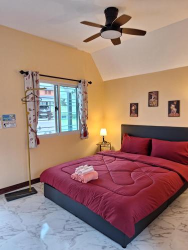 a bedroom with a large red bed with a ceiling fan at บ้านน้ำผึ้งโฮมสเตย์ in Suan Phung