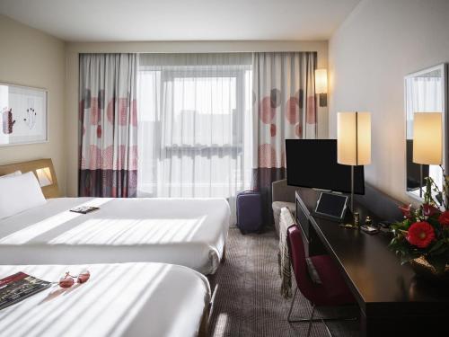 a hotel room with two beds and a desk at Novotel Reading Centre in Reading