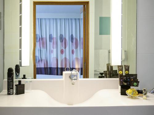 a bathroom with a sink and a large mirror at Novotel Reading Centre in Reading