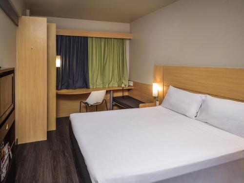 a hotel room with a large bed and a desk at ibis Aracaju in Aracaju