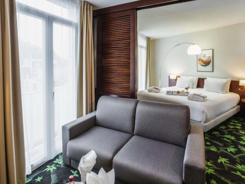 a hotel room with a bed and a couch at Mercure Lourdes Impérial in Lourdes