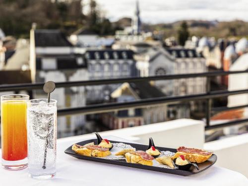 a plate of food on a table with a drink at Mercure Lourdes Impérial in Lourdes