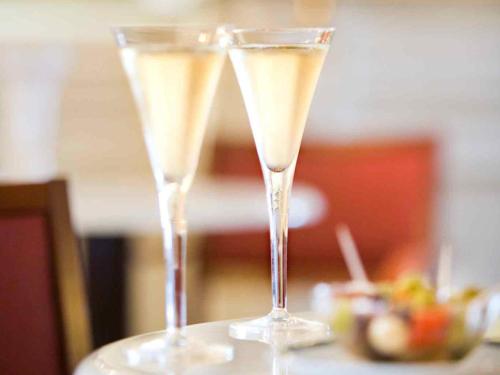 two champagne glasses sitting on top of a table at Mercure Lourdes Impérial in Lourdes