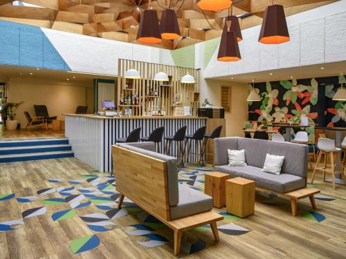 a lobby with a waiting area with chairs and a bar at ibis Styles Parc des Expositions de Villepinte in Villepinte