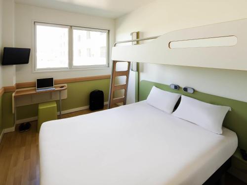 a bedroom with a bunk bed and a desk with a laptop at Ibis Budget Barcelona Viladecans in Viladecáns