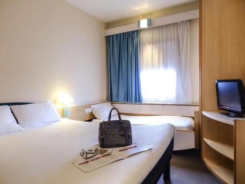 a hotel room with a bed with a bag on it at Ibis Madrid Alcorcon Tresaguas in Alcorcón