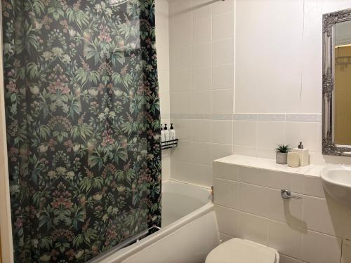 a bathroom with a shower curtain with a toilet and a sink at Lovely Room with a view & Parking nr Hampton Court in West Molesey