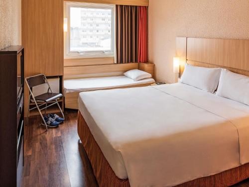 a hotel room with two beds and a window at ibis Blumenau in Blumenau