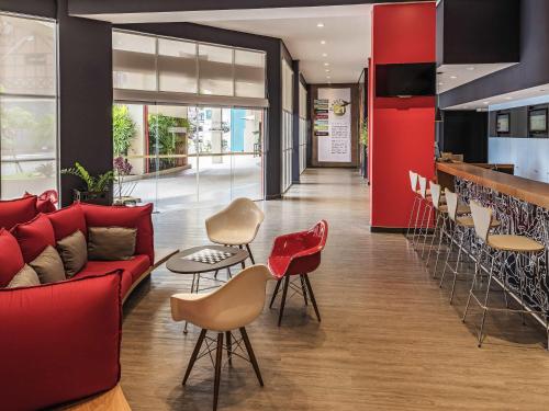 a living room with a red couch and chairs at ibis Blumenau in Blumenau