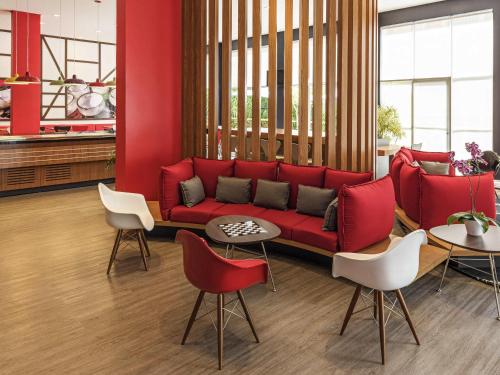 a living room with a red couch and chairs at ibis Blumenau in Blumenau
