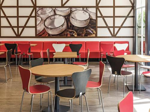a restaurant with tables and chairs in front of a wall at ibis Blumenau in Blumenau
