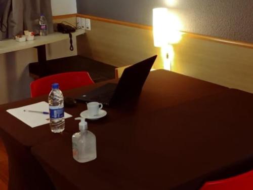 a table with a laptop and a bottle of water on it at ibis Campinas in Campinas