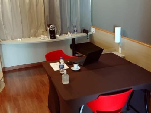 a table with two red chairs and a table with a laptop at ibis Campinas in Campinas