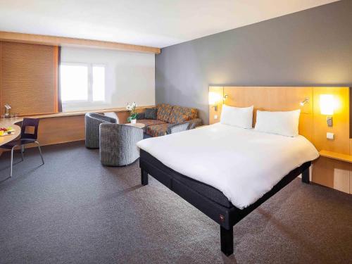 a hotel room with a large bed and a couch at Ibis Praha Old Town in Prague