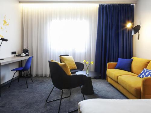 a living room with a yellow couch and chairs at Ibis Praha Old Town in Prague