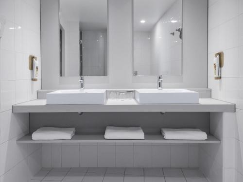 a bathroom with two sinks and two mirrors at Ibis Praha Old Town in Prague