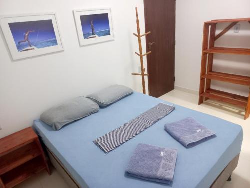 a bedroom with a blue bed with towels on it at QUARTO PRIVATIVO - RECANTO dos SONHOS - MASSARANDUPIÓ in Massarandupio