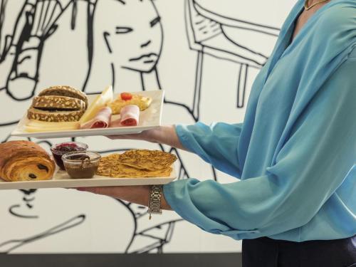 ルヴァロワ・ペレにあるibis Levallois Perretの女が食物の皿を持っている