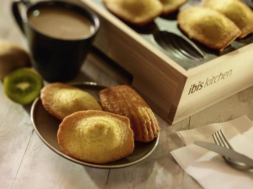 a plate of donuts next to a box with a cup of coffee at ibis Nuits Saint Georges in Nuits-Saint-Georges