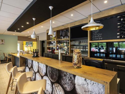 a bar with a wooden counter and chairs at ibis Nuits Saint Georges in Nuits-Saint-Georges