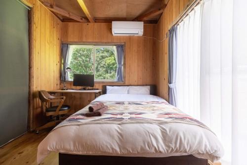 a bedroom with a bed with a desk and a window at 葉山ヒュッゲ in Hayama