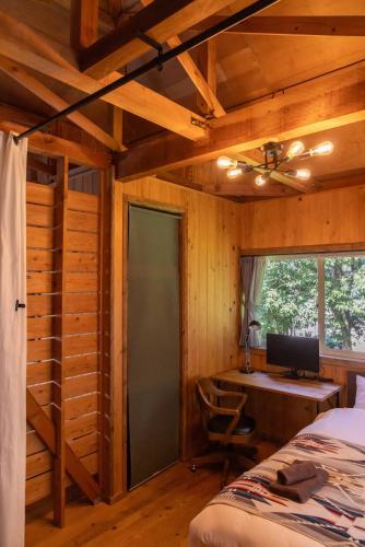 a bedroom with a bed and a desk with a computer at 葉山ヒュッゲ in Hayama
