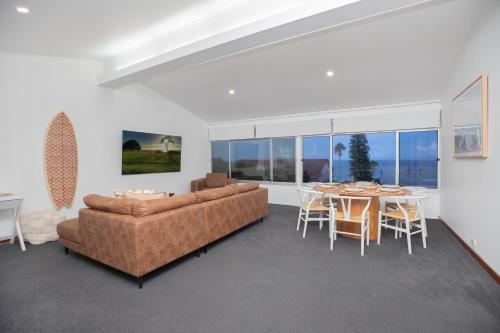 Una sala de estar con un sofá, una mesa y sillas. en One Mile Horizon - Beach House, en Forster