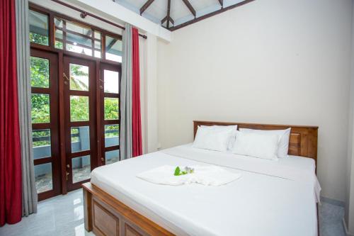 ein Schlafzimmer mit einem großen weißen Bett und einem Fenster in der Unterkunft Blue Orchid Villa in Talpe