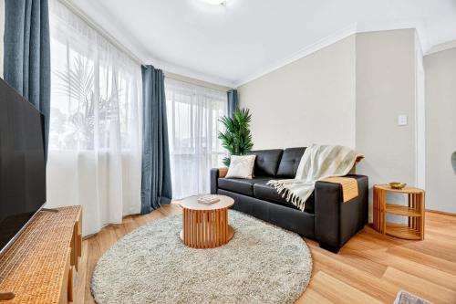 a living room with a black couch and a table at Stylish 2BR Fremantle Apartment with Pool Access in Fremantle