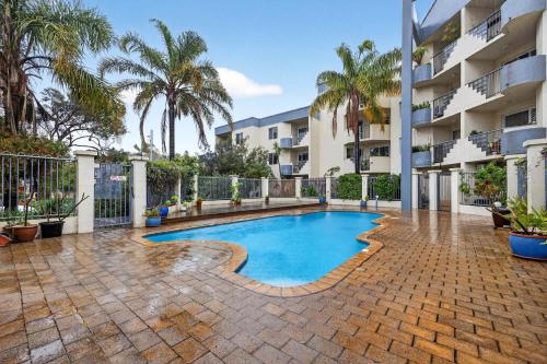 a swimming pool in the middle of a courtyard with palm trees at Stylish 2BR Fremantle Apartment with Pool Access in Fremantle