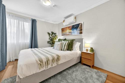 a bedroom with a large bed and a window at Stylish 2BR Fremantle Apartment with Pool Access in Fremantle