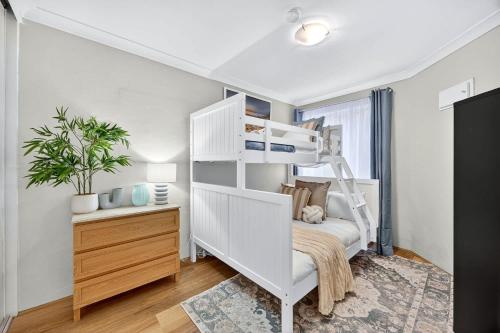 a bedroom with a white bunk bed and a desk at Stylish 2BR Fremantle Apartment with Pool Access in Fremantle