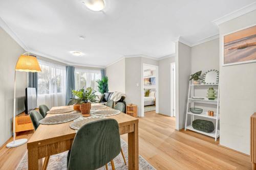 a dining room and living room with a table and chairs at Stylish 2BR Fremantle Apartment with Pool Access in Fremantle