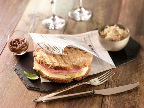 a sandwich on a black plate with a fork and knife at ibis La Ciotat in La Ciotat