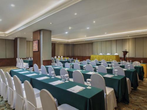 a banquet hall with green tables and white chairs at Novotel Semarang in Semarang