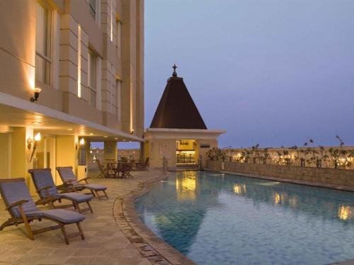 a hotel with a swimming pool next to a building at Novotel Semarang in Semarang