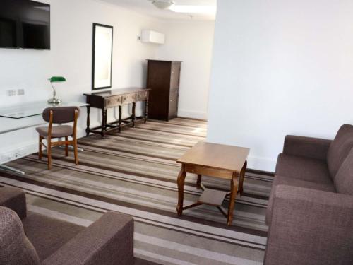 a living room with a couch and a table and a piano at Mercure Canberra in Canberra