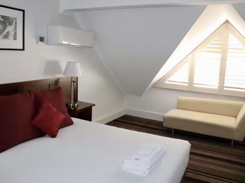 a bedroom with a bed and a window and a chair at Mercure Canberra in Canberra
